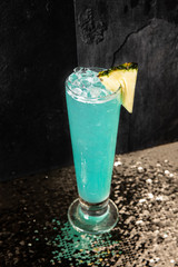 Cocktail drink on a old stone board. Alcoholic beverage with tropical fruits red pepper herb and ice. cocktail in glass on black background. Copyspace. Close up of glass of cocktail 