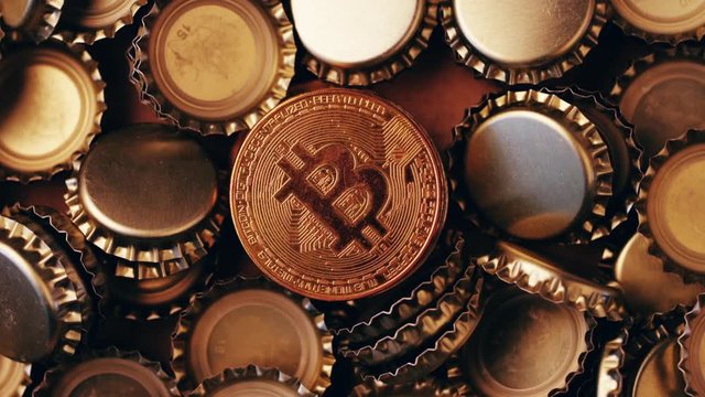 Bitcoin token coins with pile of beer bottle crown caps, top view