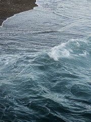 Ola del mar expandiéndose sobre la arena de la playa en la costa.