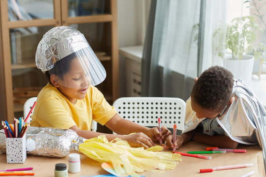 Portrait of two African-American boys playing astronauts and making space suits while enjoying art and craft lesson in preschool or development center, copy space