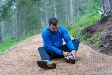 Young athlete in blue sports wear sitting on the ground he injured ankle.