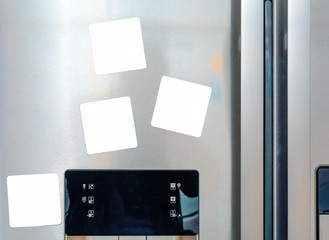 Four blank white paper notes attached on gray refrigerator door