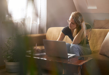 Young woman working from home on sofa