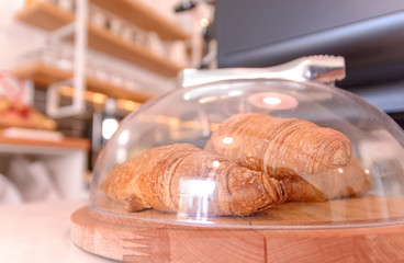 Freshly baked croissants on wooden cutting board in cafeteria