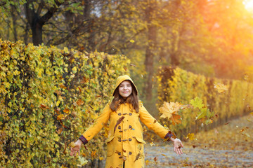 autumn leaves fall around teenage girl in the park
