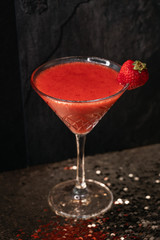 Cocktail drink on a old stone board. Alcoholic beverage with tropical fruits red pepper herb and ice. cocktail in glass on black background. Copyspace. Close up of glass of cocktail 