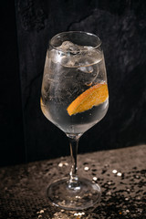 Cocktail drink on a old stone board. Alcoholic beverage with tropical fruits red pepper herb and ice. cocktail in glass on black background. Copyspace. Close up of glass of cocktail 