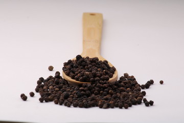 black pepper in wooden spoon isolated on white background.