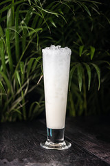 Cocktail drink on a old stone board. Alcoholic beverage with tropical fruits red pepper herb and ice. cocktail in glass on black background. Copyspace. Close up of glass of cocktail 