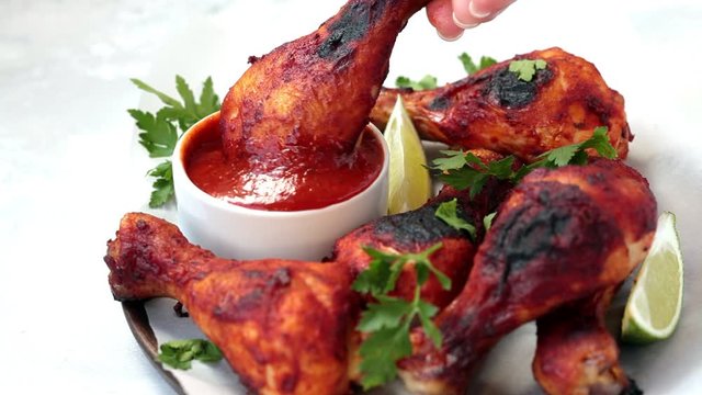 Baked chicken legs in tomato sauce or barbecue sauce on wooden plate.