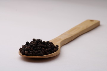 black pepper in wooden spoon isolated on white background.