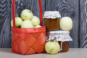 Apples in a red wicker basket. Jam in jars and apples nearby. Fruit harvest.