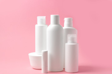 Set of white cosmetic bottles and jars on pink background with place to add text