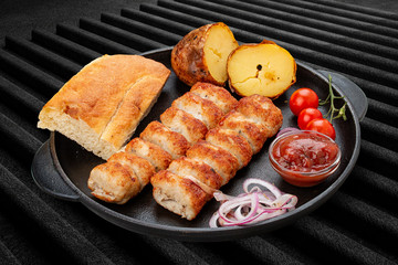 Lula kebab with grilled potatoes, matnakash and red sauce. Served in a cast iron pan