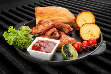 Grilled chicken wings with baked potatoes, matnakash and red sauce. Served in a cast iron pan