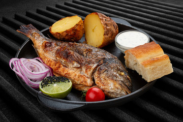 Grilled dorado with baked potatoes, matnakash and red sauce. Served in a cast iron pan
