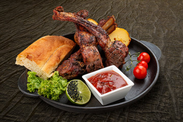 Grilled lamb rack with baked potatoes, matnakash and red sauce. Served in a cast iron pan