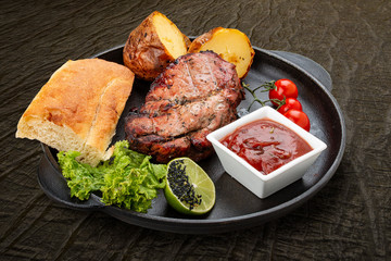 Grilled veal steak with baked potatoes, matnakash and red sauce. Served in a cast iron pan