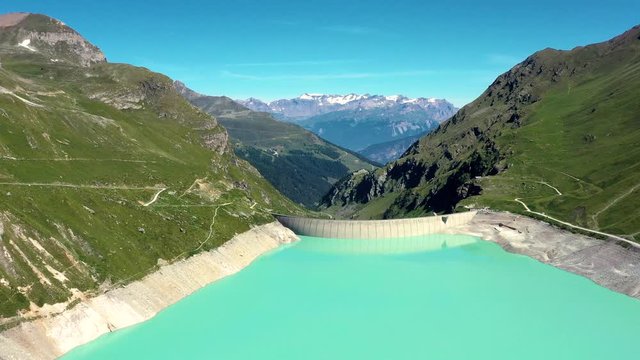 Aerial view with a drone over Moiry Dam in the middle of a valley. Renewable Energy and Electric Power technology scene. Beautiful landscape view in the background - Aerial 4k