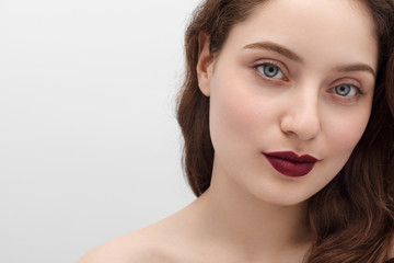 Young girl with burgundy lipstick on her lips, long hair, close-up. Young girl with long hair and blue eyes.