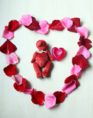 red rose petals and toy teddy bear on white background