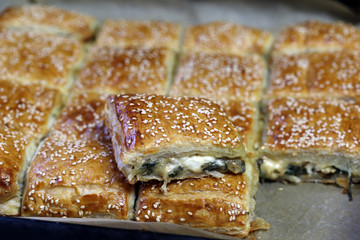 urekas. Puff pastry pies with spinach with spinach, salted cheese, and sesame