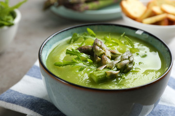 Delicious asparagus soup served on table, closeup