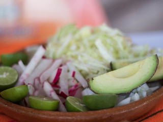 Plato de barro con aguacate, rábanos, limones y lechuga 