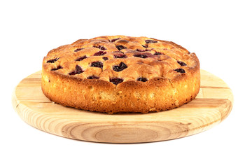 A whole pie with cherries on a cutting board over a white background.