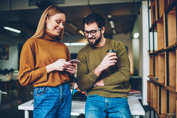 Man with coffee and woman enjoying free time at comfortable office while hipster girl holding...