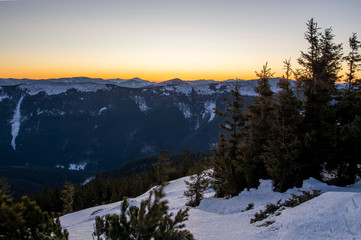 Sunset in the mountains. Mountainous relief with snow. Peaks of the mountains.