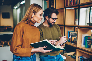 Positive man and woman preparing for exam spending time at university campus, successful male and...