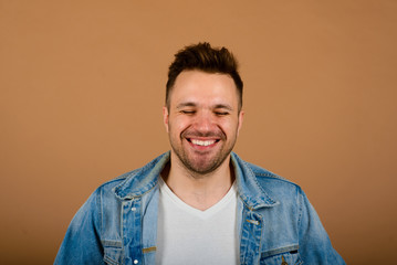 Handsome man standing and smiling isolated on light brown studio background. Male half-length portrait. The human emotions, facial expression concept. Front view.