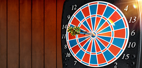 Close up of a Dart machine. In the dartboard are dart arrows. Copy Space.