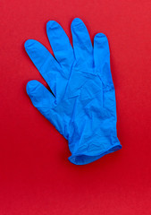 A blue latex medical glove on a red background 