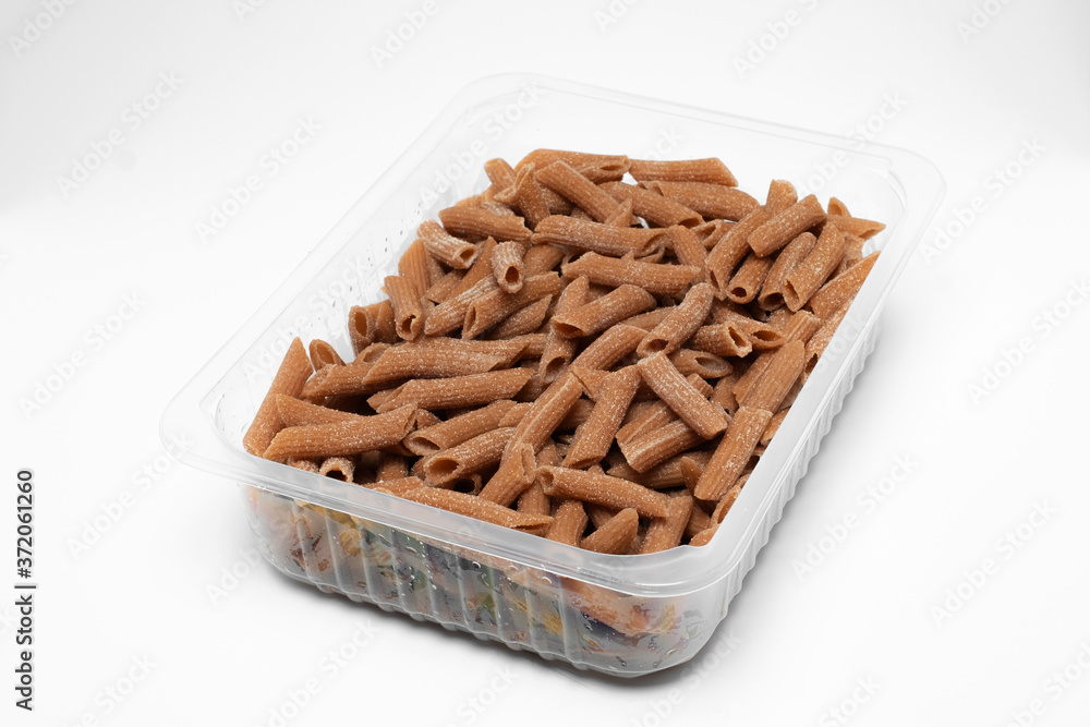 Wall mural Raw Wholegrain penne pasta in a plastic box isolated on a white background