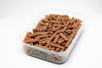 Raw Wholegrain penne pasta in a plastic box isolated on a white background