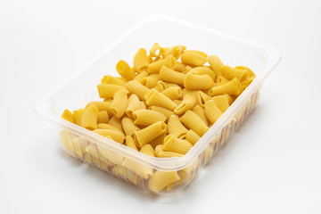 Raw Rigatoni pasta in a plastic box isolated on a white background