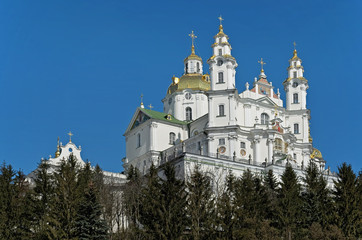 Fototapeta na wymiar Dormition Cathedral of Holy Dormition Pochayiv Lavra, Ukraine seen over the pinewood.