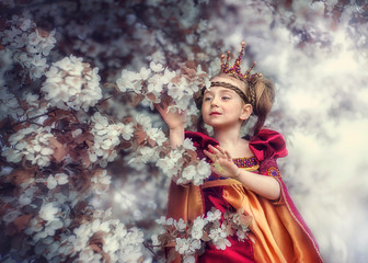 Fototapeta premium A little Princess in Apple blossom touches the flowers.
