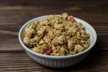 granola in a white bowl with pieces of tropical fruits