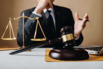 Justice and law concept.Male judge in a courtroom with the gavel, working with, computer and...