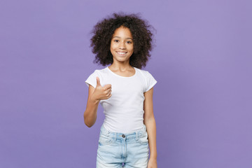 Smiling little african american kid girl 12-13 years old in white t-shirt isolated on pastel violet wall background studio portrait. Childhood lifestyle concept. Mock up copy space. Showing thumb up.