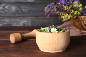 Mortar with healing herbs and pestle on wooden table