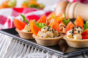 delicious snack tartlets on rustic wooden background