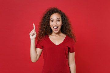 Excited young african american woman girl in casual t-shirt posing isolated on red background studio portrait. People lifestyle concept. Mock up copy space. Hold index finger up with great new idea.