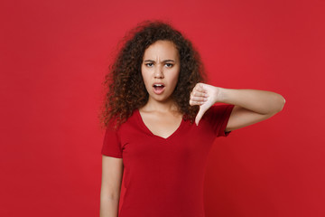 Dissatisfied young african american woman girl in casual t-shirt posing isolated on red background...