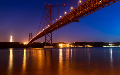 Fototapeta na wymiar View of the Tagus River and the 25 of April Bridge (Ponte 25 de Abril) at night, in Lisbon, Portugal