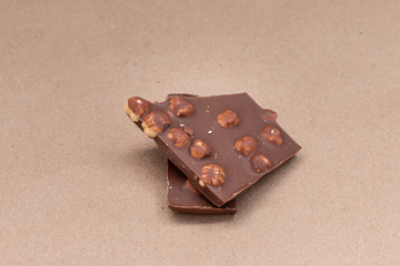 broken chocolate with hazelnuts on beige background

