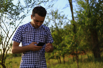 Young white Caucasian man, freelancer with the phone tensely solves business issues while in nature...